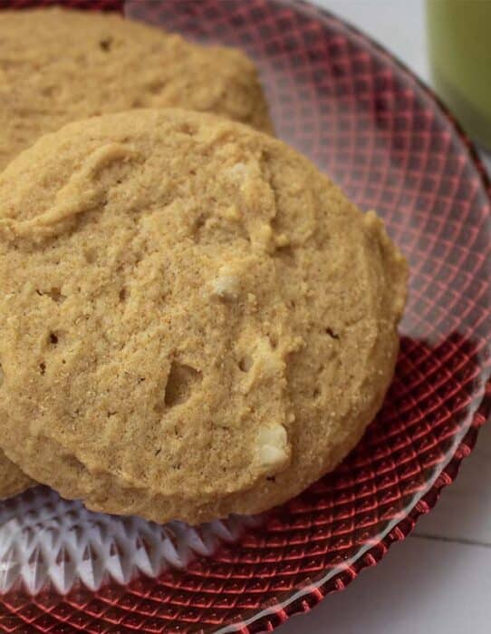 Galleta de macadamia servida sobre plato rojo de vidrio