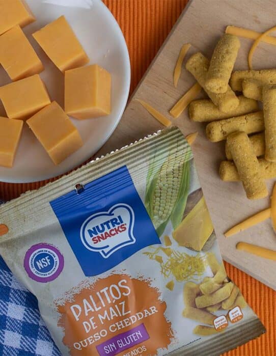 Palitos cheddar Nutrisnacks servidos junto a queso en cuadritos y empaque Nutrisnacks