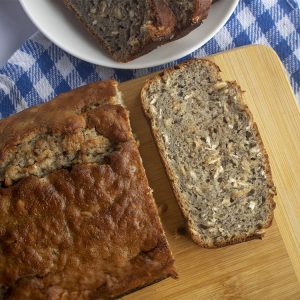 Pan de banano servido sobre tabla de bambú y mantel de cuadros azules